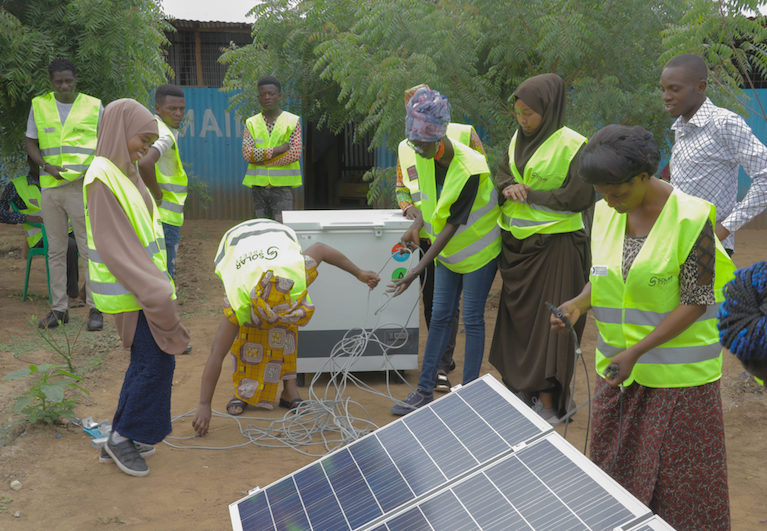 A group of young people setting up a solar panel