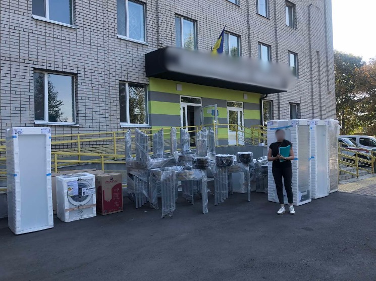 Photo of a woman standing in front of a shelter with new equipment and appliances  for the facility