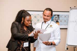 a woman showing a man some notes on a piece of paper. 