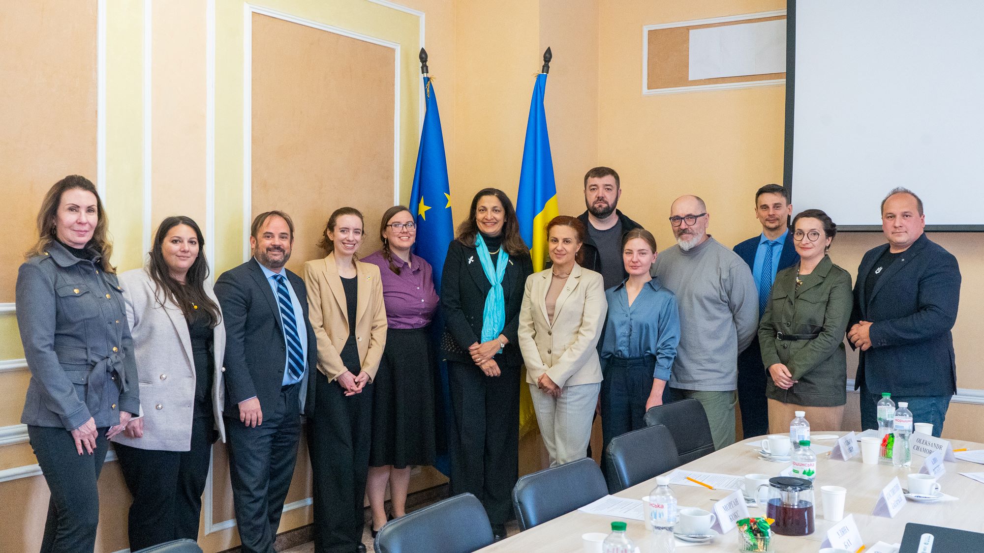 Image of male and female colleagues standing together in a board room in front of the Ukrainian flag  