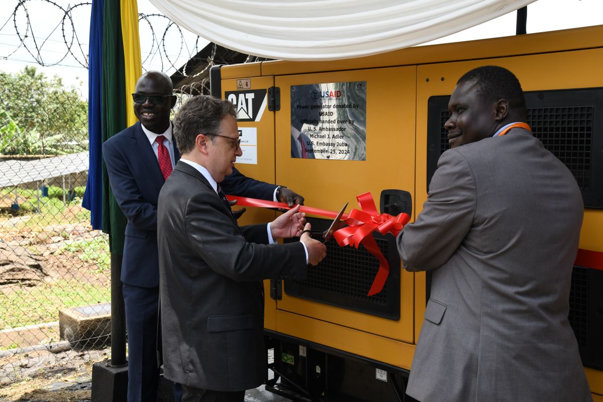 A group of men cutting a red ribbon