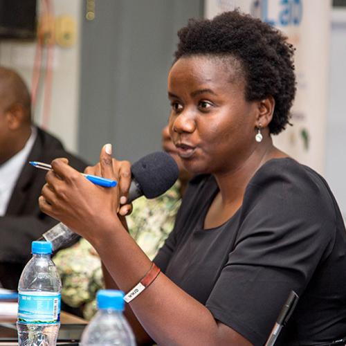 A panelist who is holding a microphone and addressing an audience.